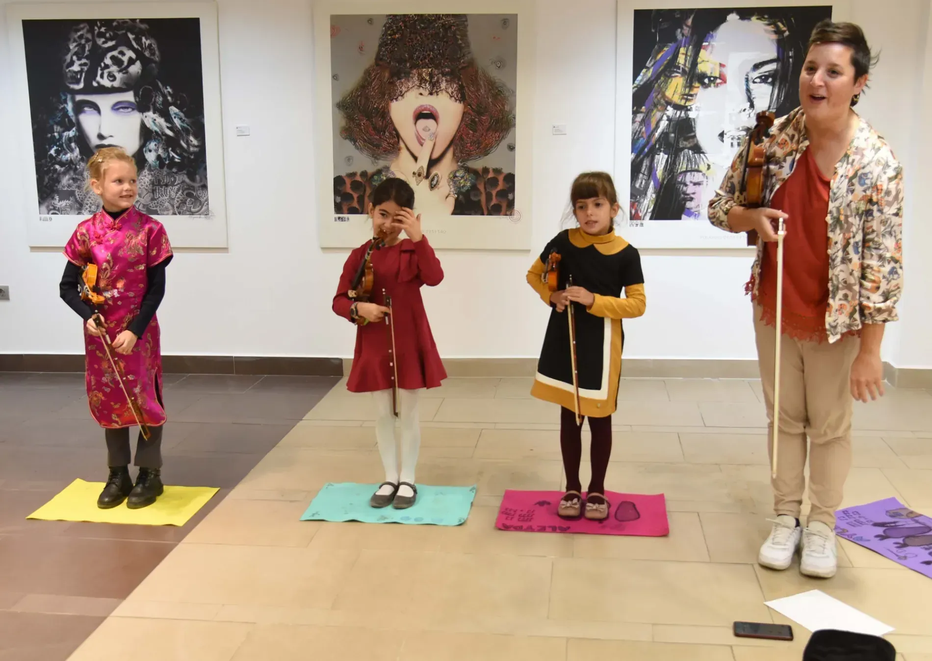 Un grupo de chicas jóvenes están de pie en una habitación con pinturas en la pared.