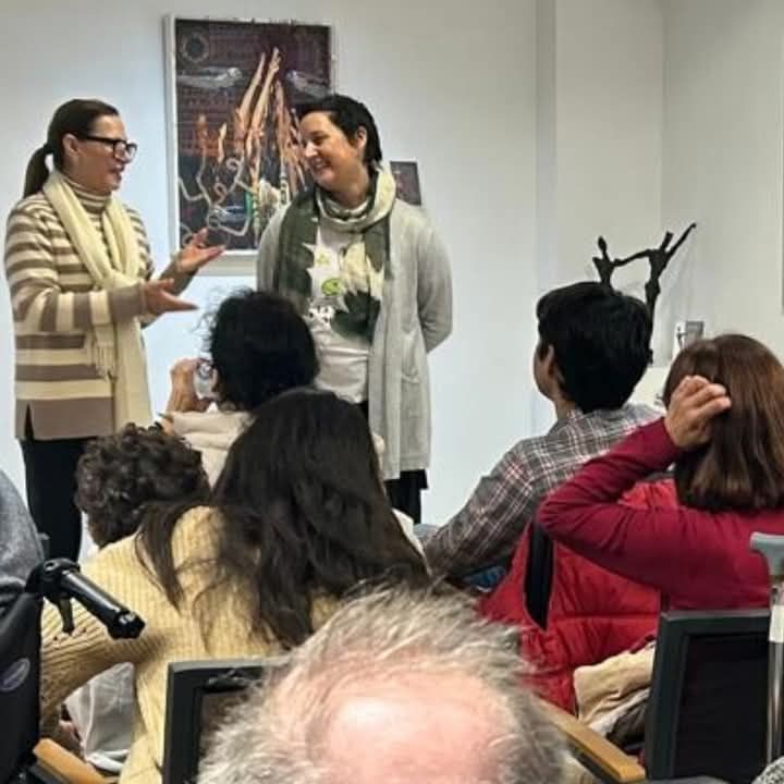 Dos mujeres están hablando con un grupo de personas en una habitación.