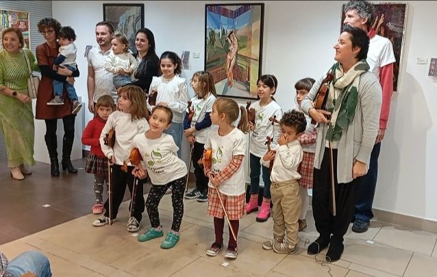 Un grupo de personas está de pie en una habitación con pinturas en la pared.