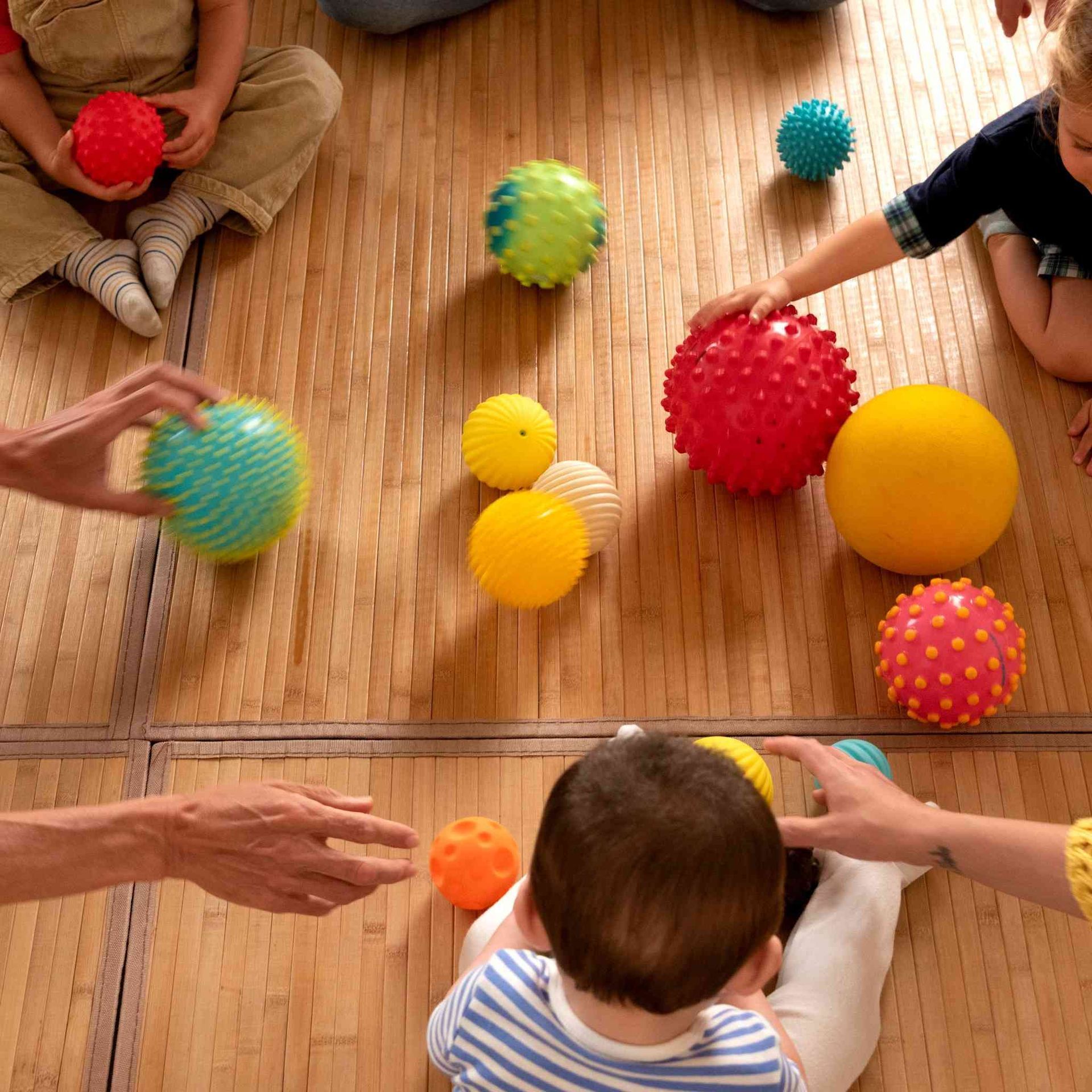 Un grupo de niños está jugando con pelotas en el suelo.