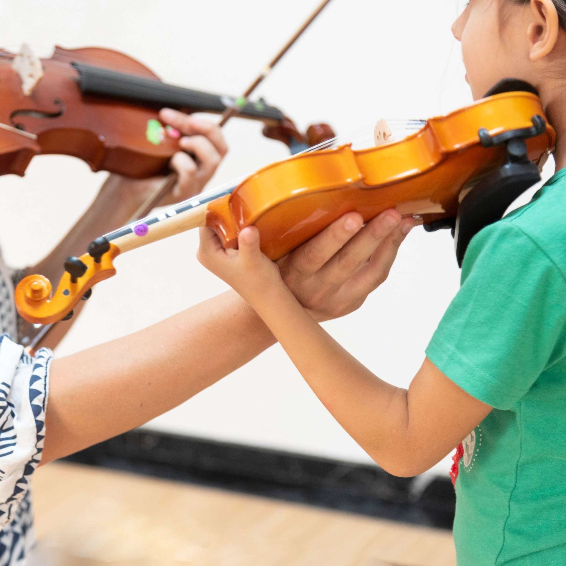 Una chica con una camisa verde está tocando un violín