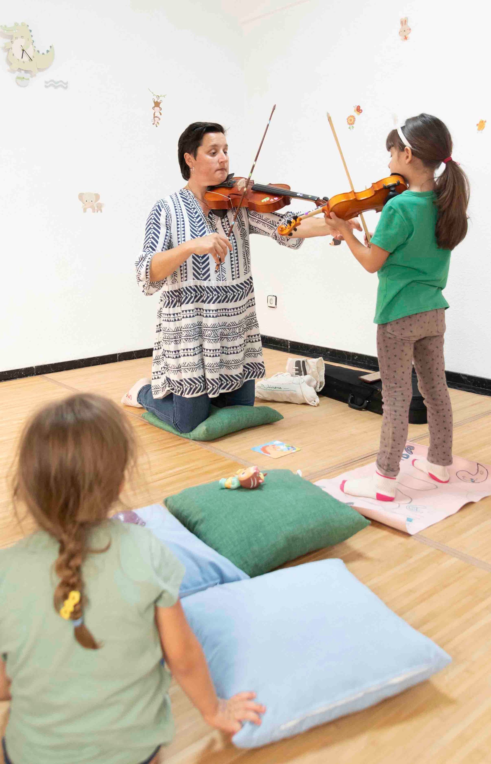 Una mujer le está enseñando a una niña a tocar el violín.
