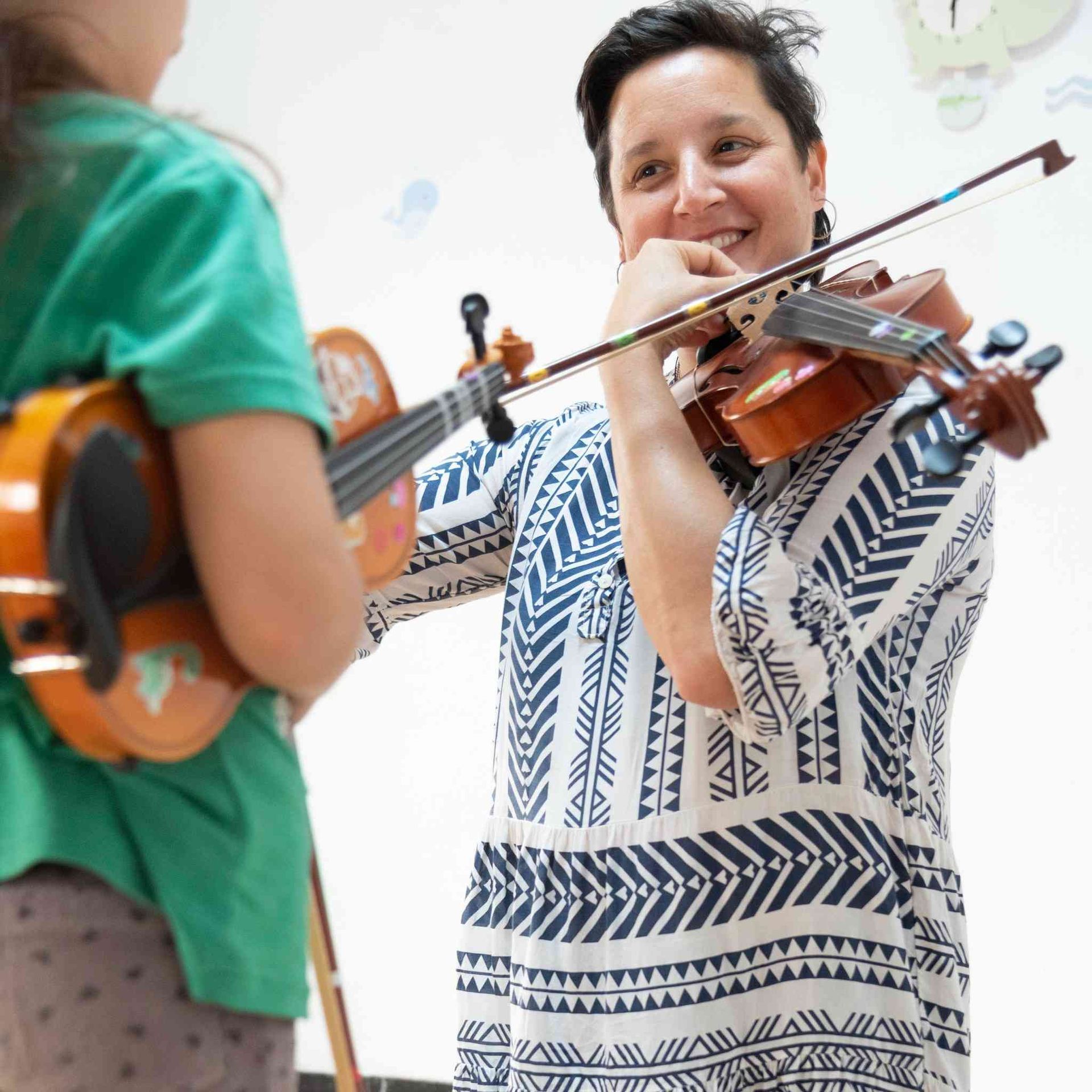 Una mujer con un vestido azul y blanco está tocando un violín.
