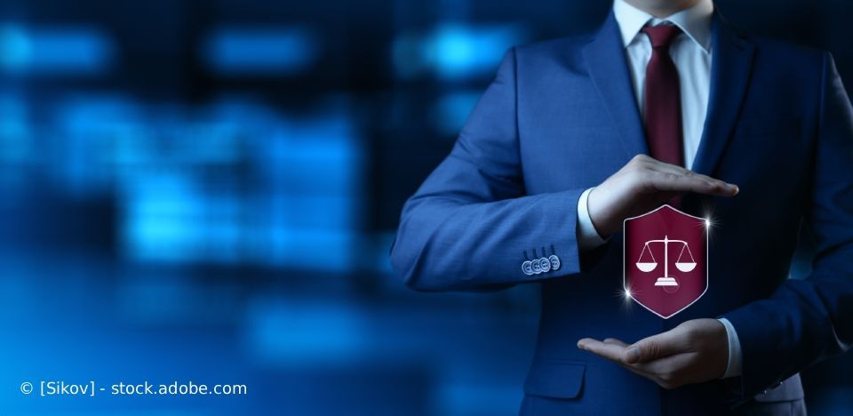 Geschäftsmann im Anzug hält ein Schild mit Schuppen, das Rechtsschutz darstellt. Blauer Hintergrund.