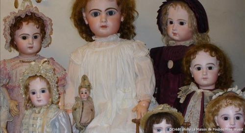 Un groupe de poupées en porcelaine antiques avec des visages peints et des vêtements élaborés.