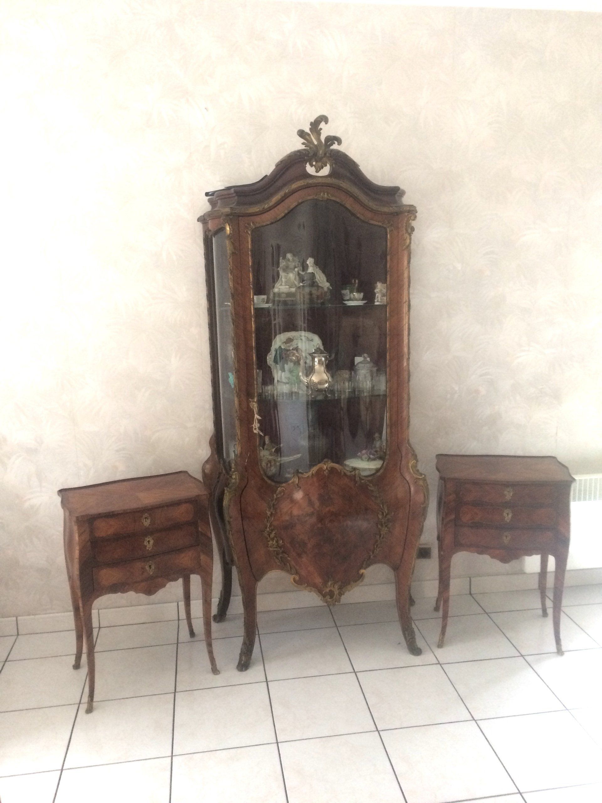Une vitrine antique en bois avec deux tables de chevet assorties devant un mur.