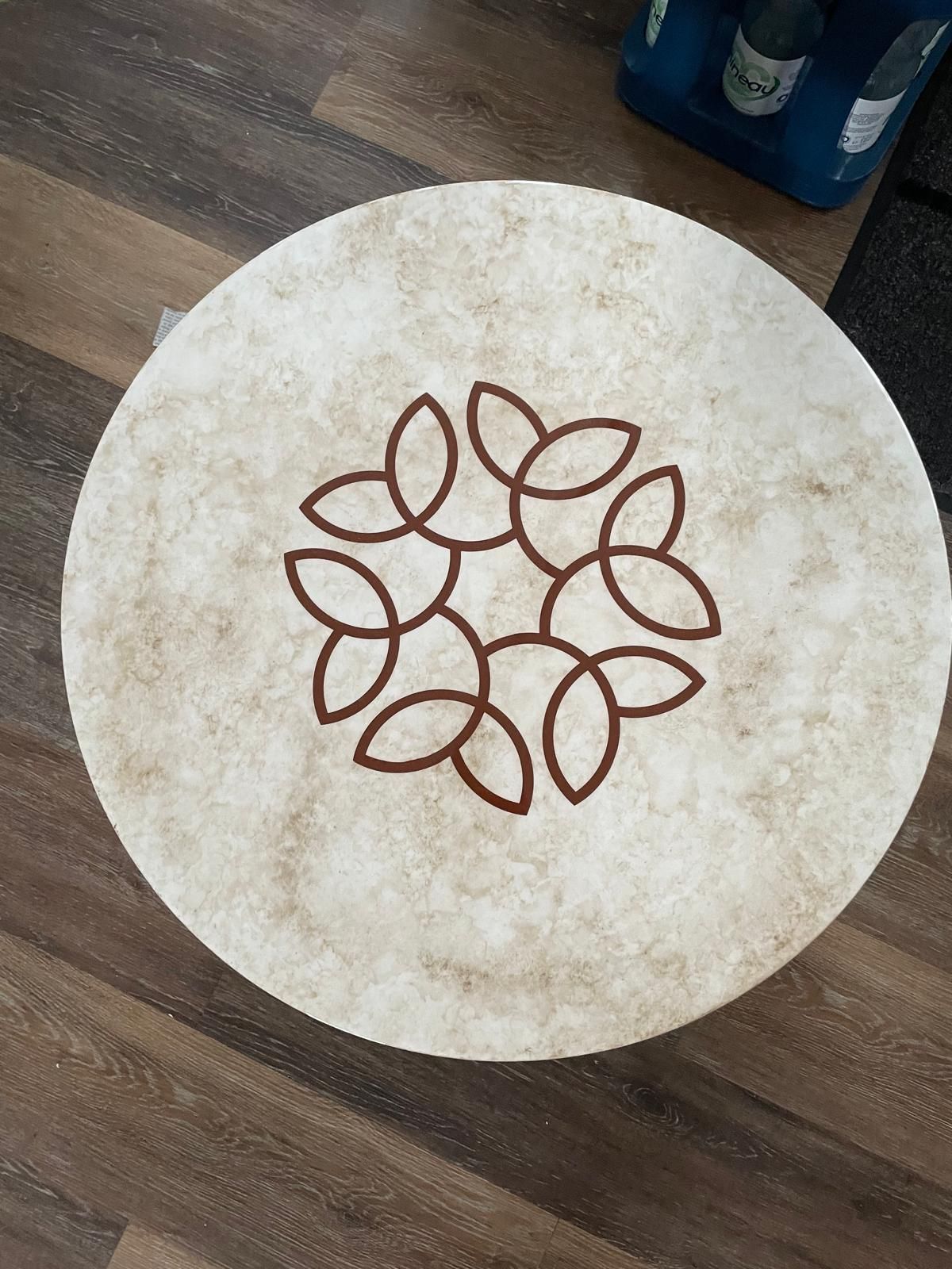 Auf einem Holzboden liegt ein runder Teppich mit Blumenmuster.