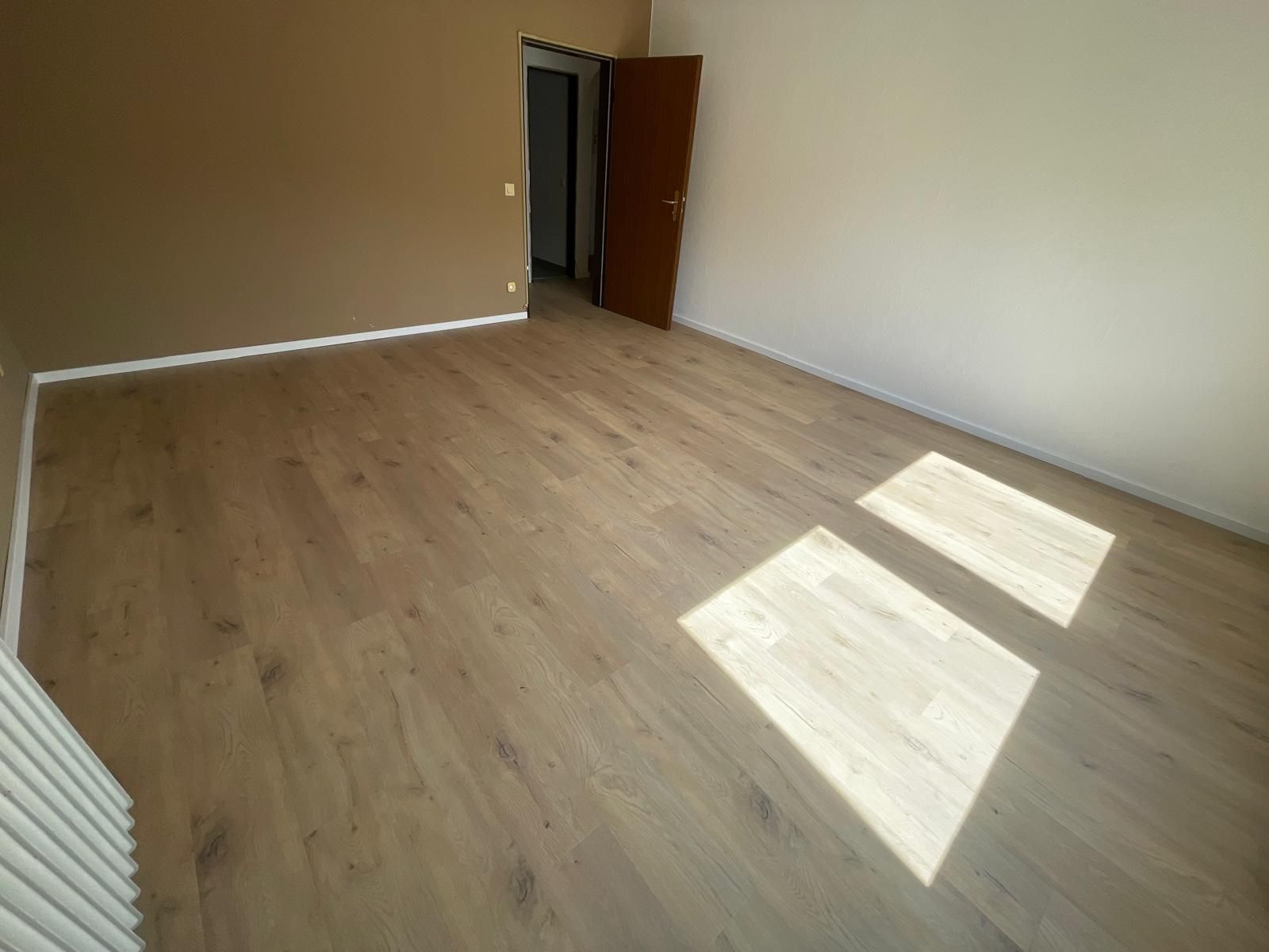Ein großer leerer Raum mit Hartholzböden und einer Tür.