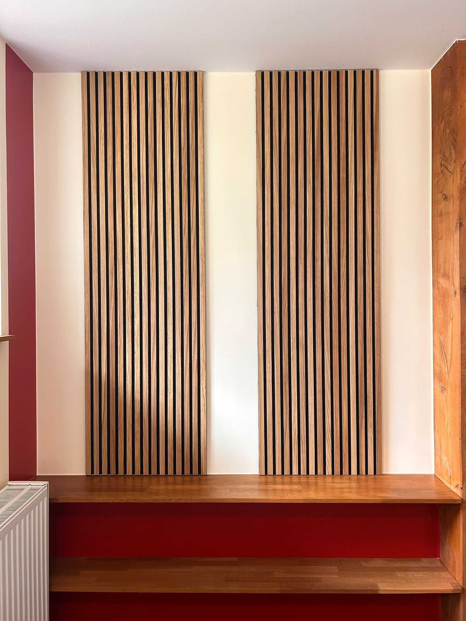 Ein Zimmer mit einem Holzregal und zwei Holzvorhängen an der Wand.