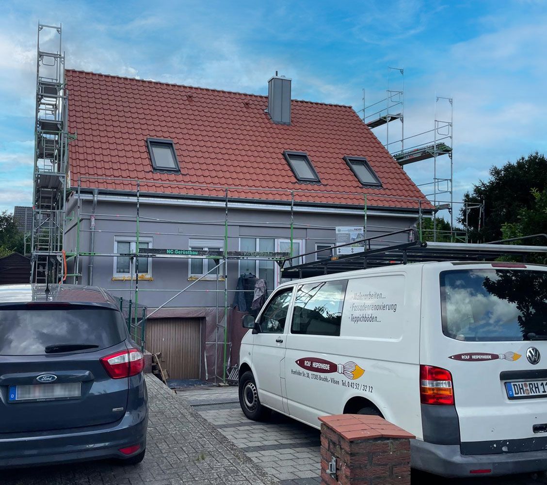 Ein weißer Lieferwagen parkt vor einem im Bau befindlichen Haus.