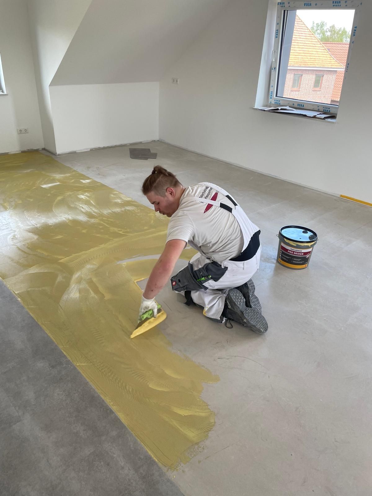 Ein Mann kniet auf dem Boden und trägt eine gelbe Beschichtung auf.
