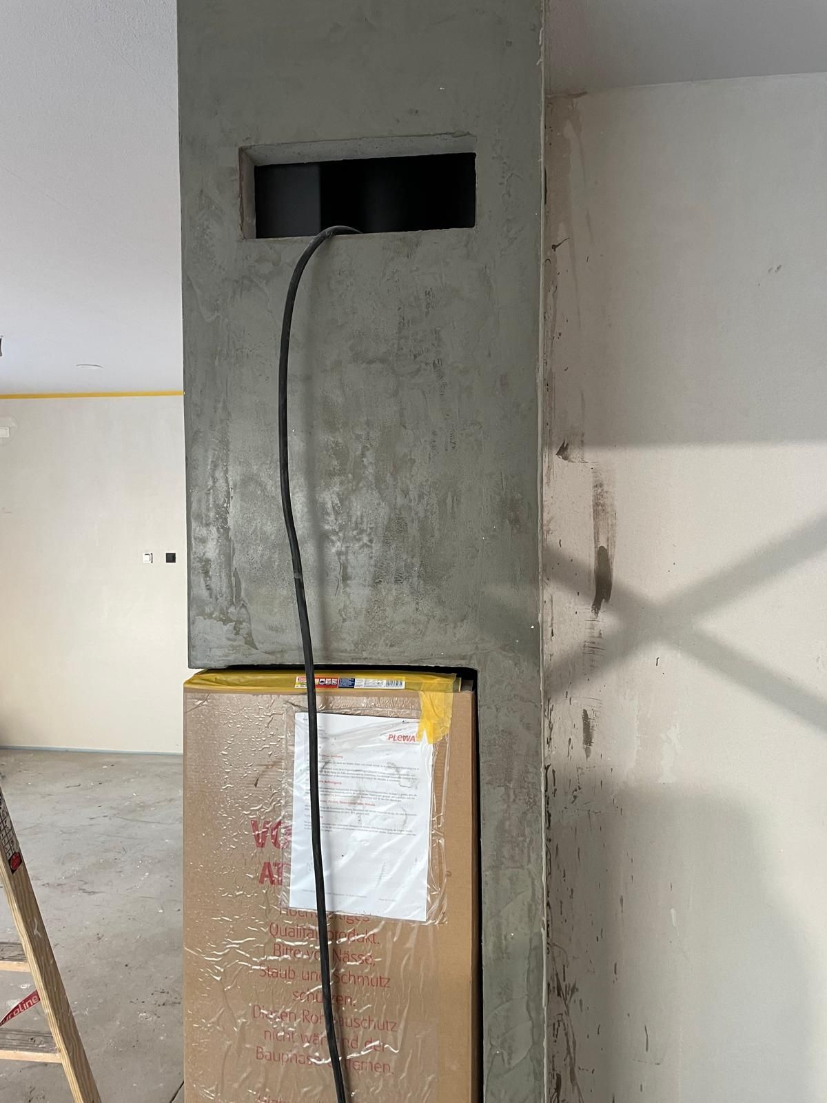 In einem Raum steht eine Leiter neben einem Karton.