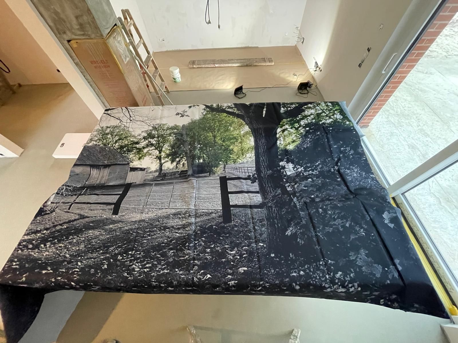 In einem Zimmer liegt auf dem Boden ein Bild eines Baumes.