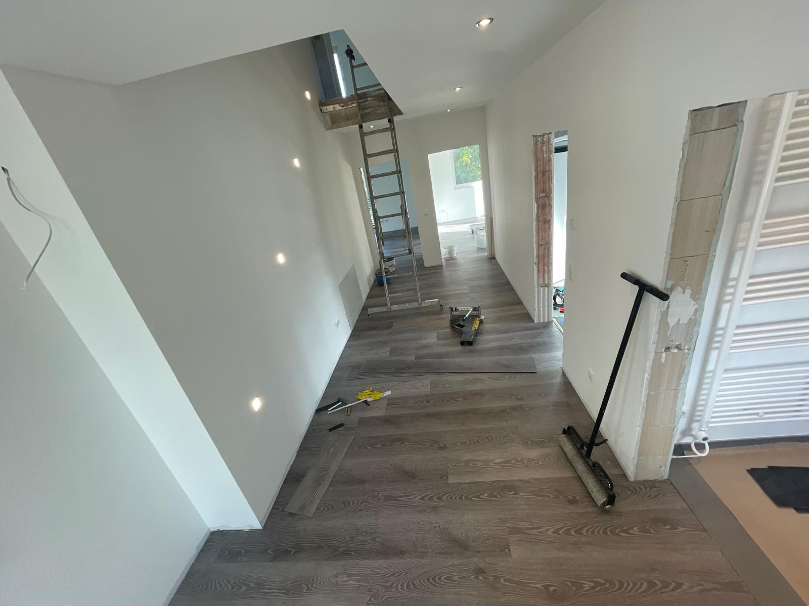 Ein Flur mit einer Leiter und einem Besen auf dem Boden.