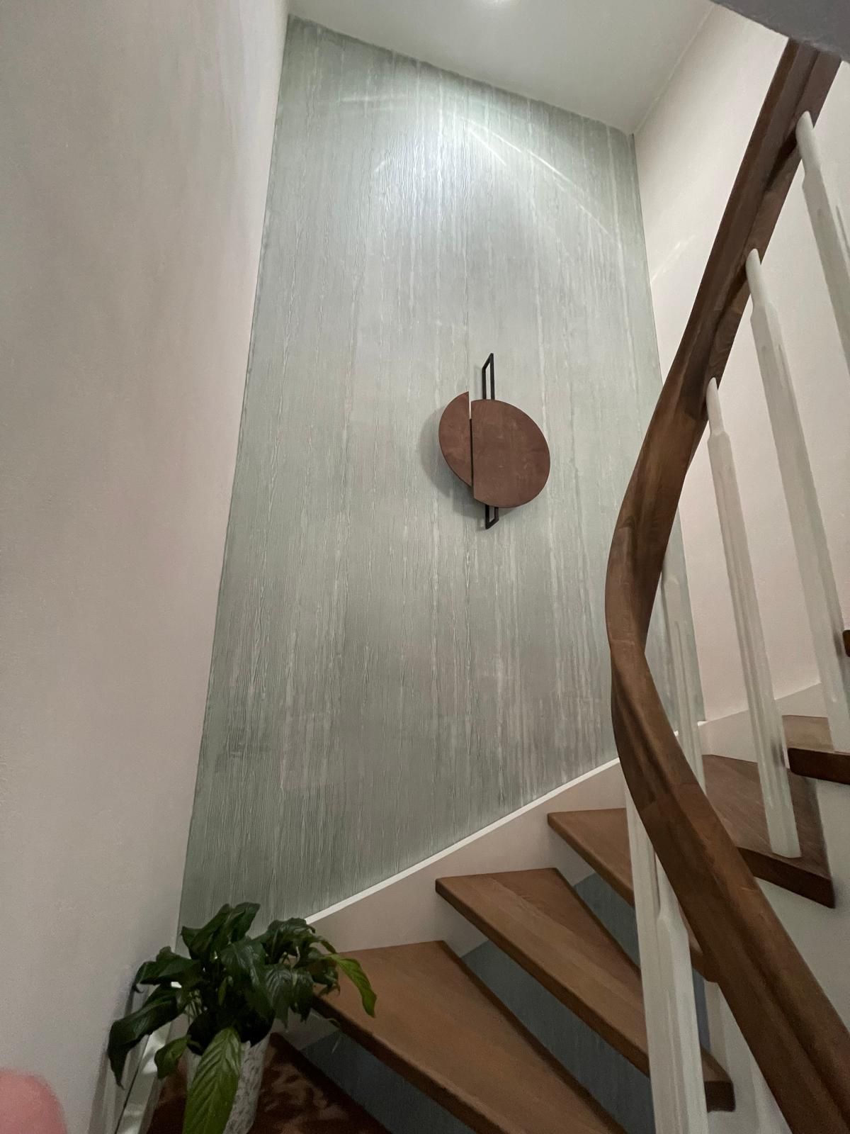 Eine Treppe mit einem Holzgeländer und einer Uhr an der Wand.