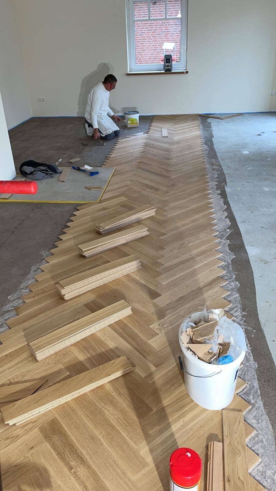 Ein Mann verlegt in einem Raum einen Holzboden.