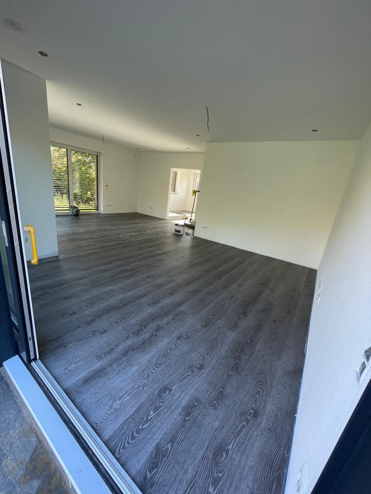 Ein großer, leerer Raum mit Holzboden und weißen Wänden.