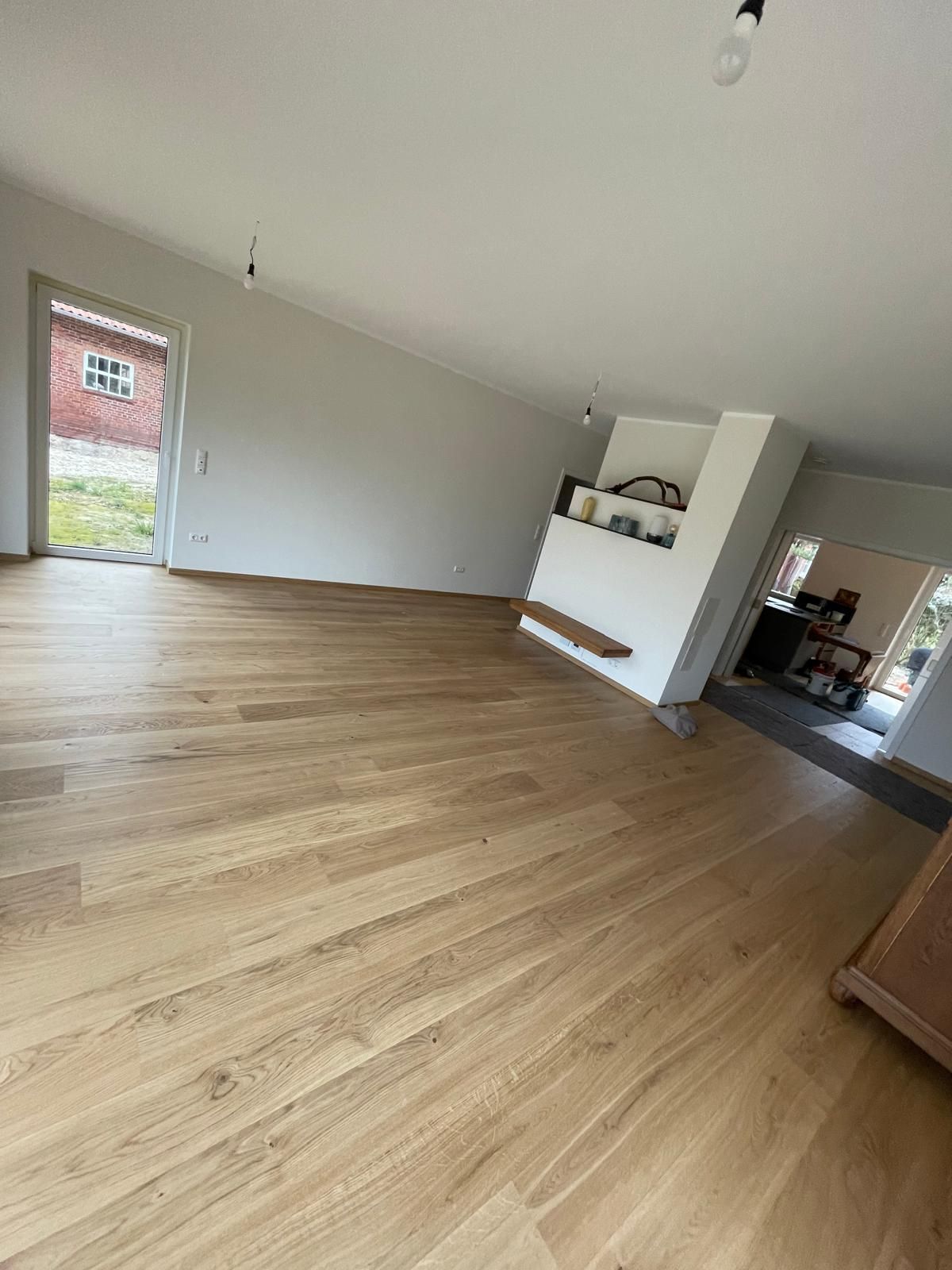 Ein Wohnzimmer mit Holzboden und weißen Wänden.