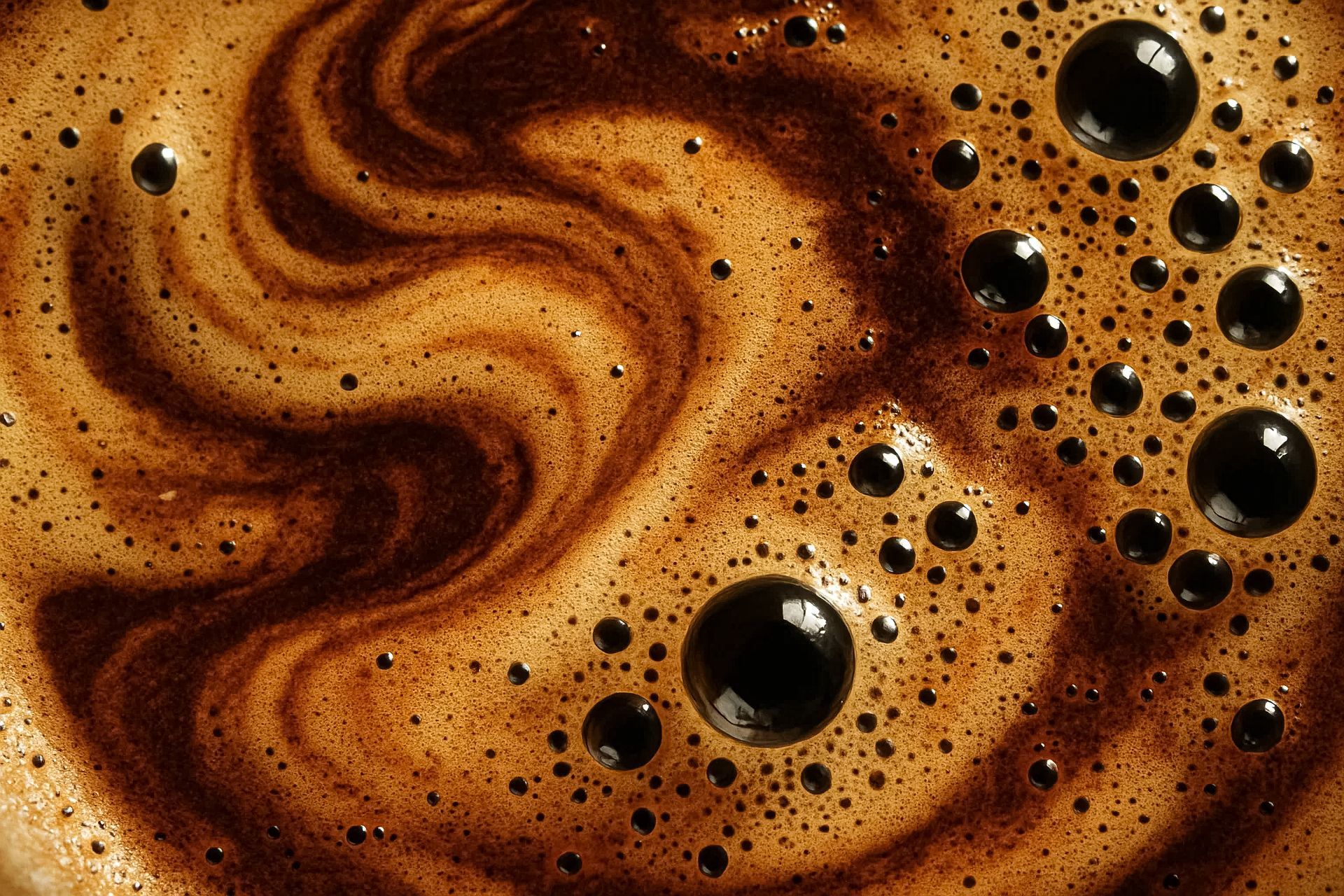 Gros plan, vue de dessus, d'un café noir avec une mousse brun clair tourbillonnante et des bulles foncées.