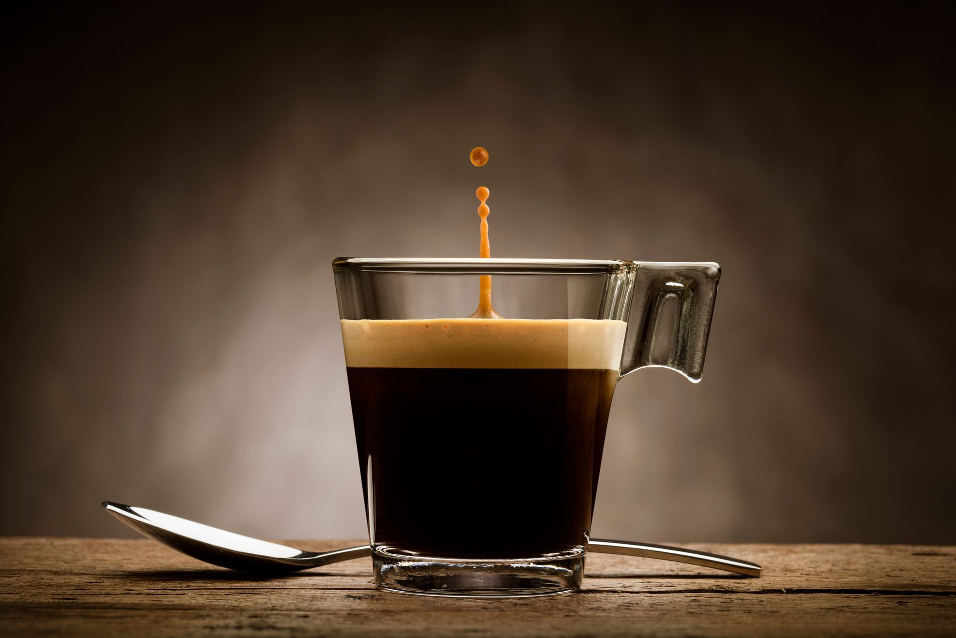 Une tasse en verre transparente contenant un expresso noir.
