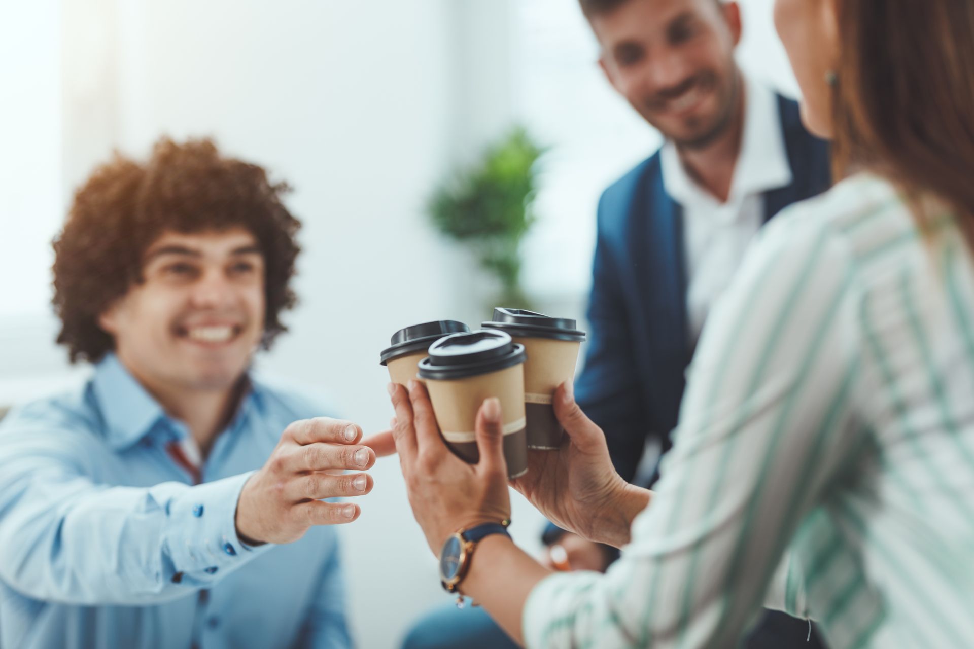 Une personne offre plusieurs gobelets de café en carton.
