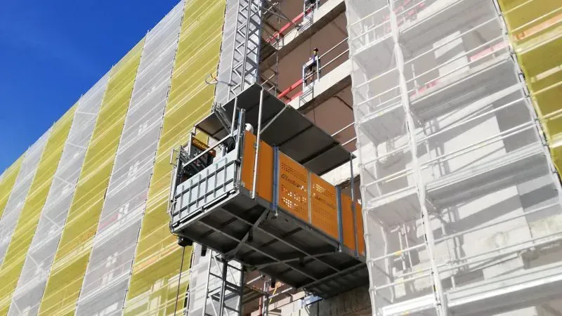 Una grúa de construcción está fijada al costado de un edificio.
