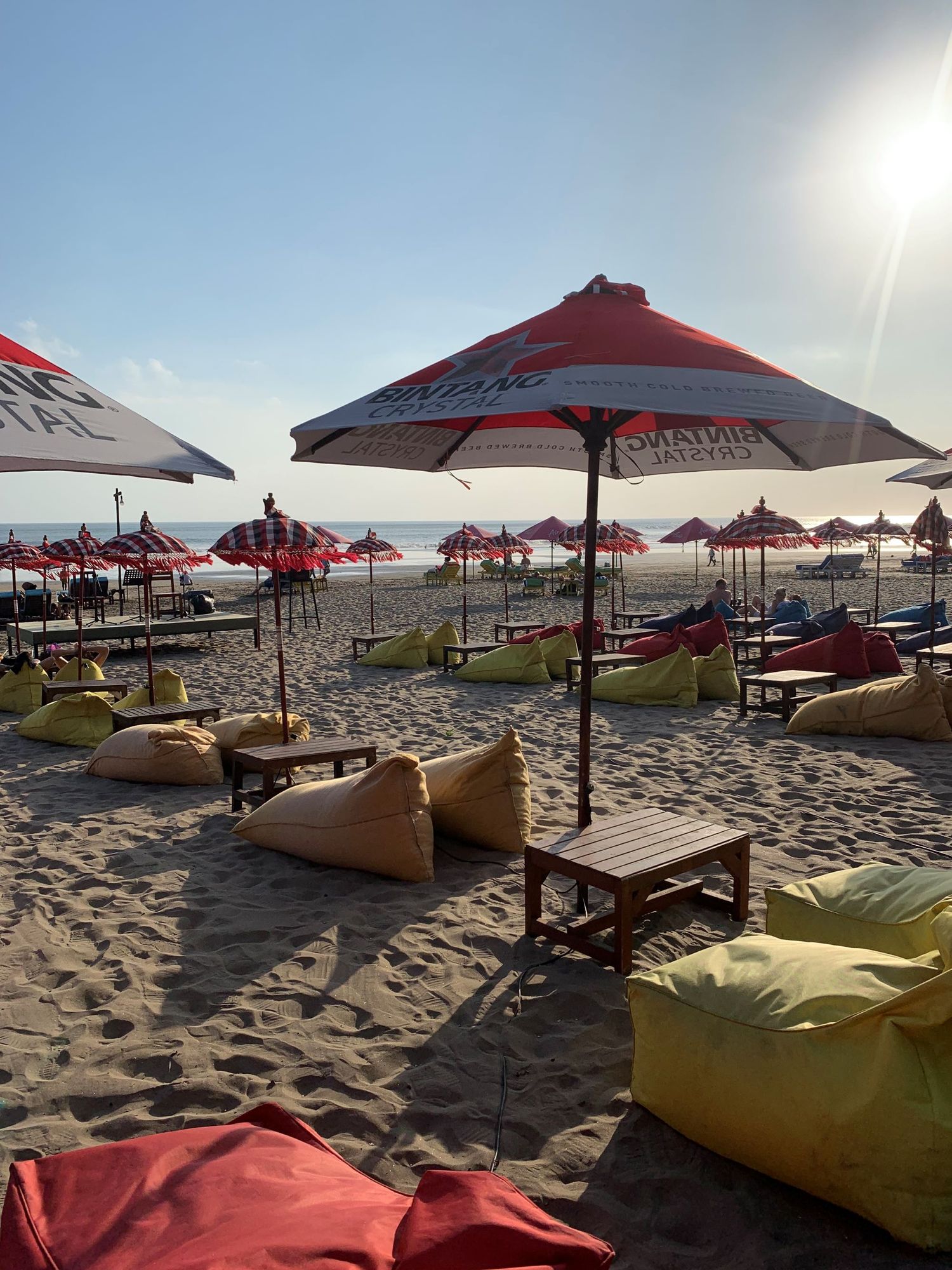 A beach with a lot of umbrellas and bean bag chairs