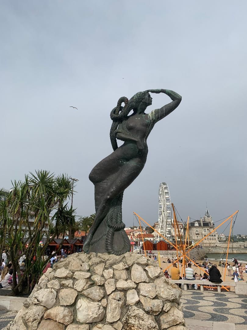 A statue of a woman standing on top of a pile of rocks.