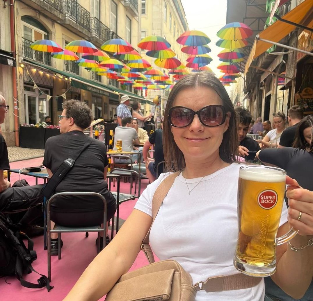 A woman is sitting at a table holding a glass of beer.