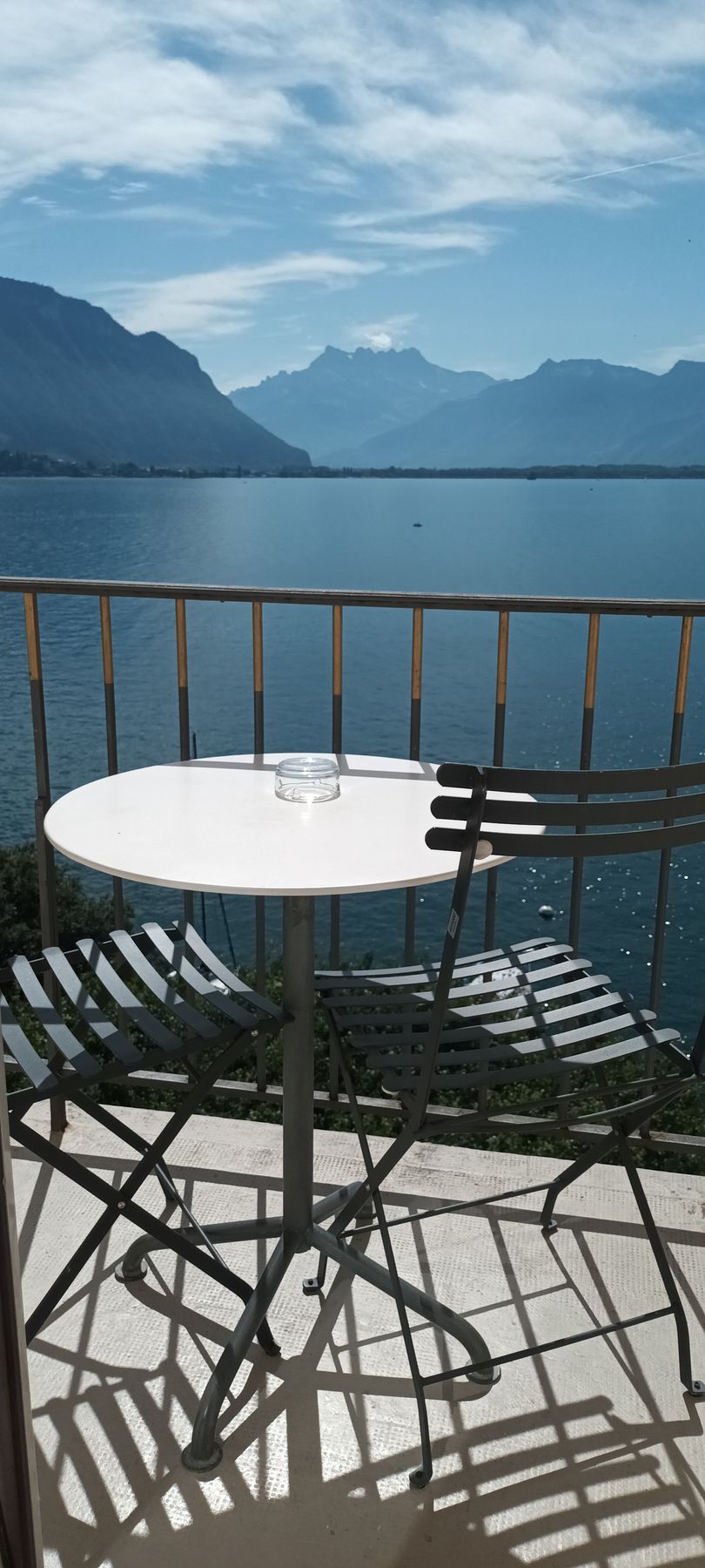 A table and chairs on a balcony overlooking a lake