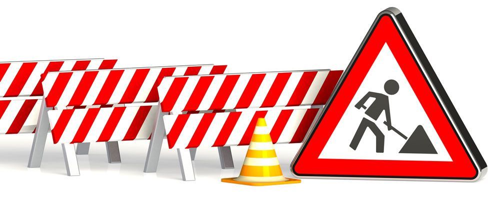 Baustellenszene mit Absperrungen, Leitkegeln und einem Baustellenschild.