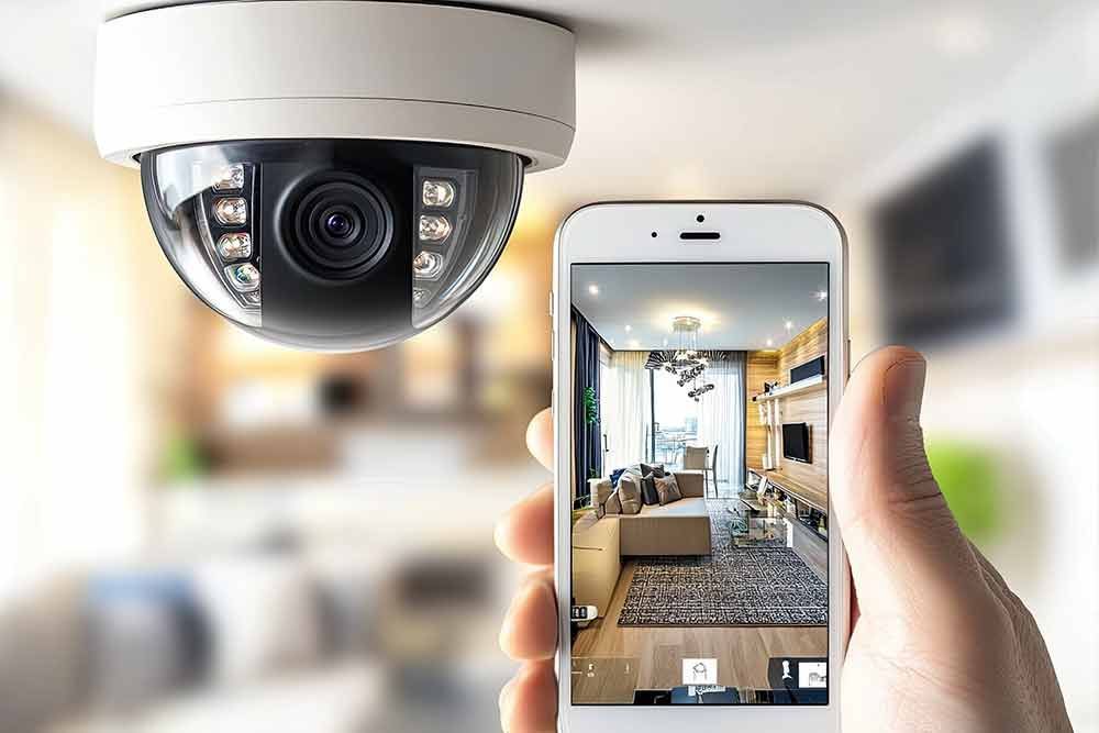 Eine Person hält ein Mobiltelefon vor eine Überwachungskamera.