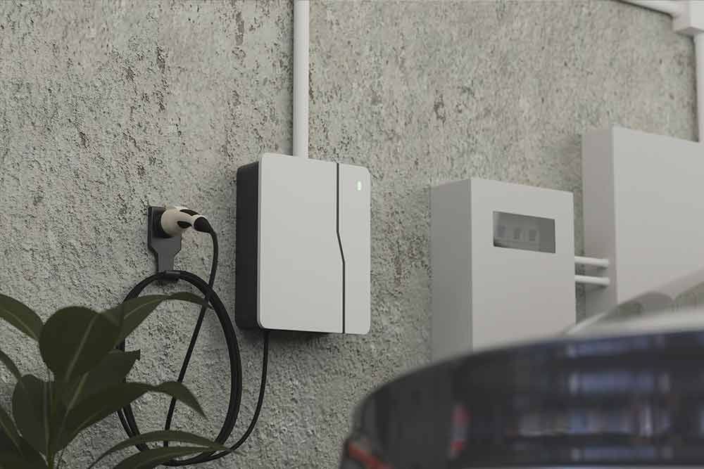 An einer Ladestation an der Seite eines Gebäudes wird ein Auto aufgeladen.