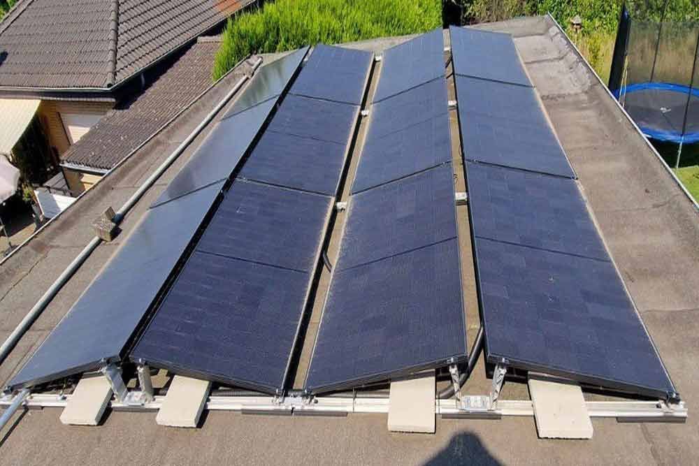 Eine Reihe von Solarmodulen auf einem Dach mit einem Trampolin im Hintergrund