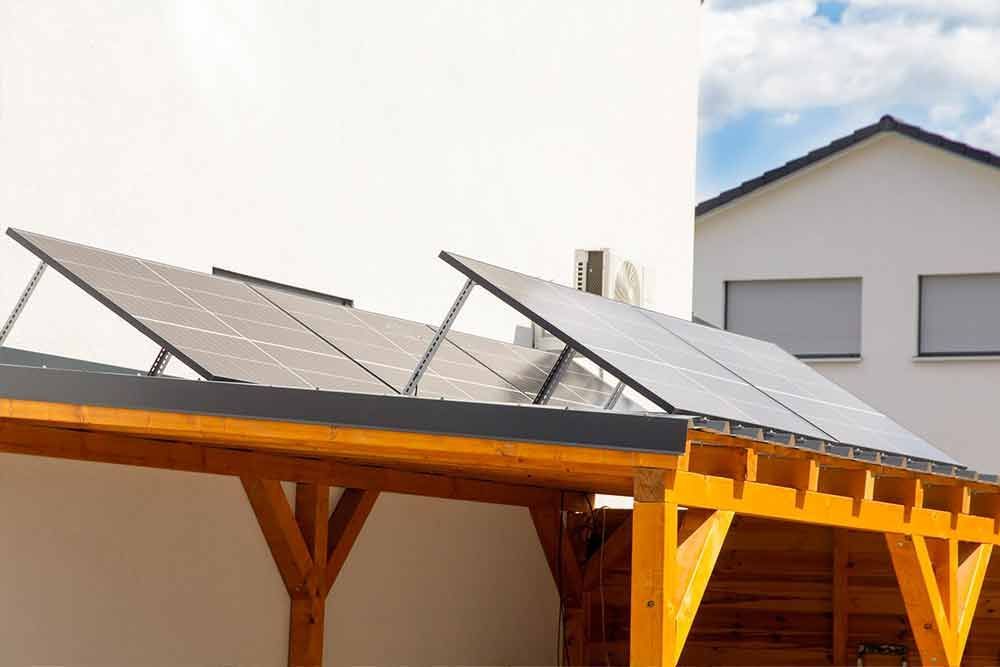 Ein Holzcarport mit Solarmodulen auf dem Dach.