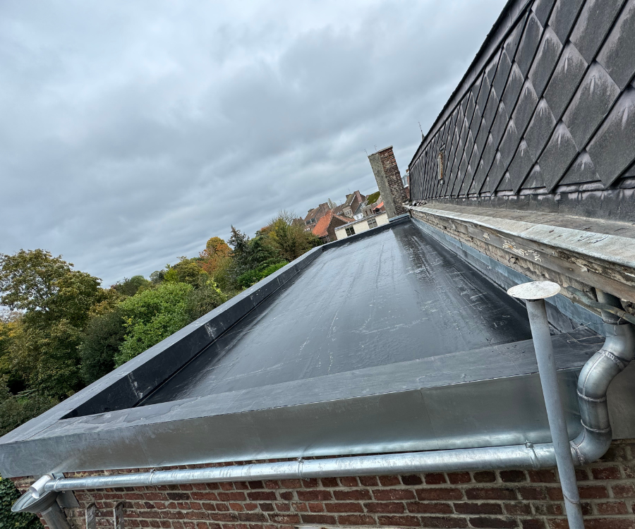 Le toit d'un bâtiment en briques avec un toit noir et des gouttières.
