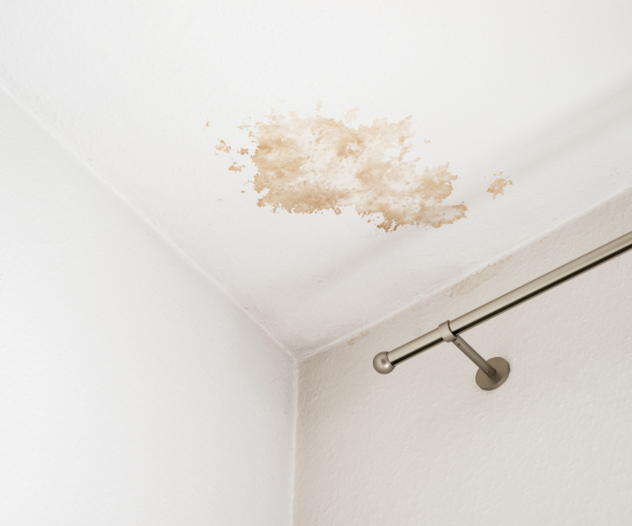 Un plafond avec une tache dessus et une tringle à rideau.