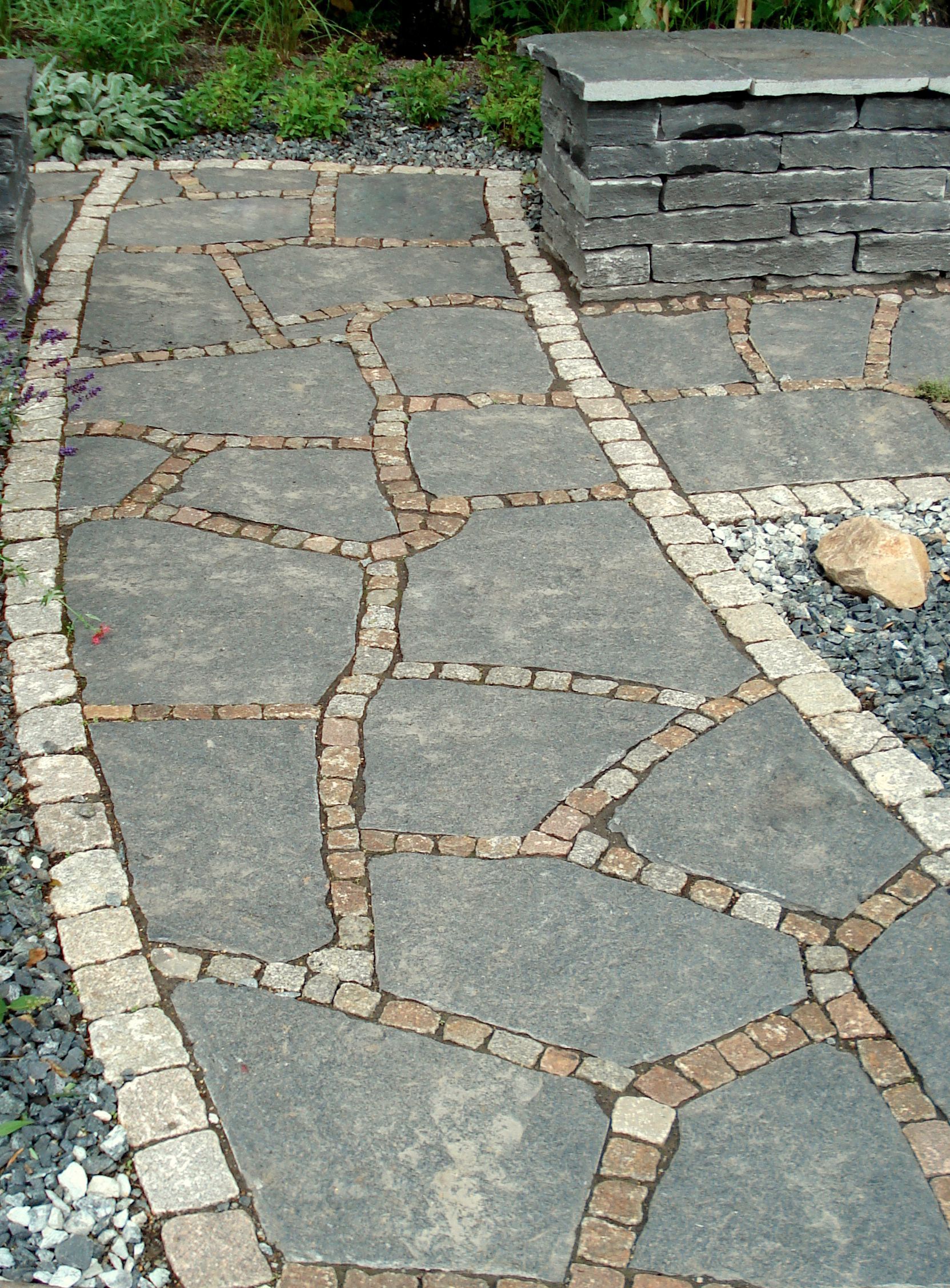 Kopfsteinpflasterhof mit zwei unterschiedlichen Pflasterstilen, getrennt durch eine Grenze. Im Hintergrund Gebäude.