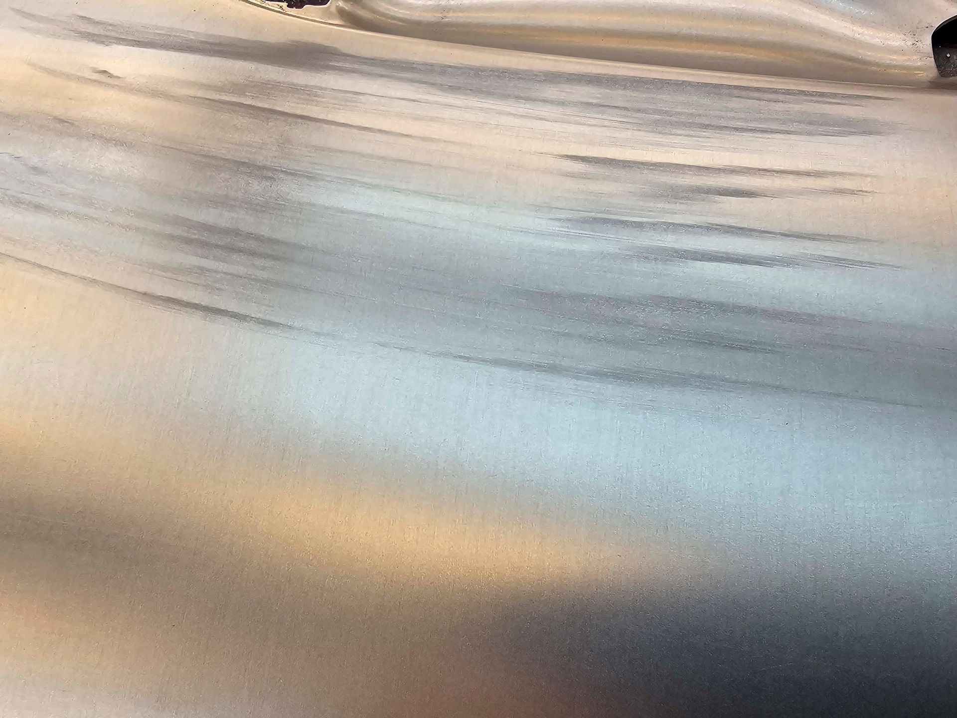 Eine Nahaufnahme einer Metalloberfläche mit der Spiegelung eines Autos darauf.