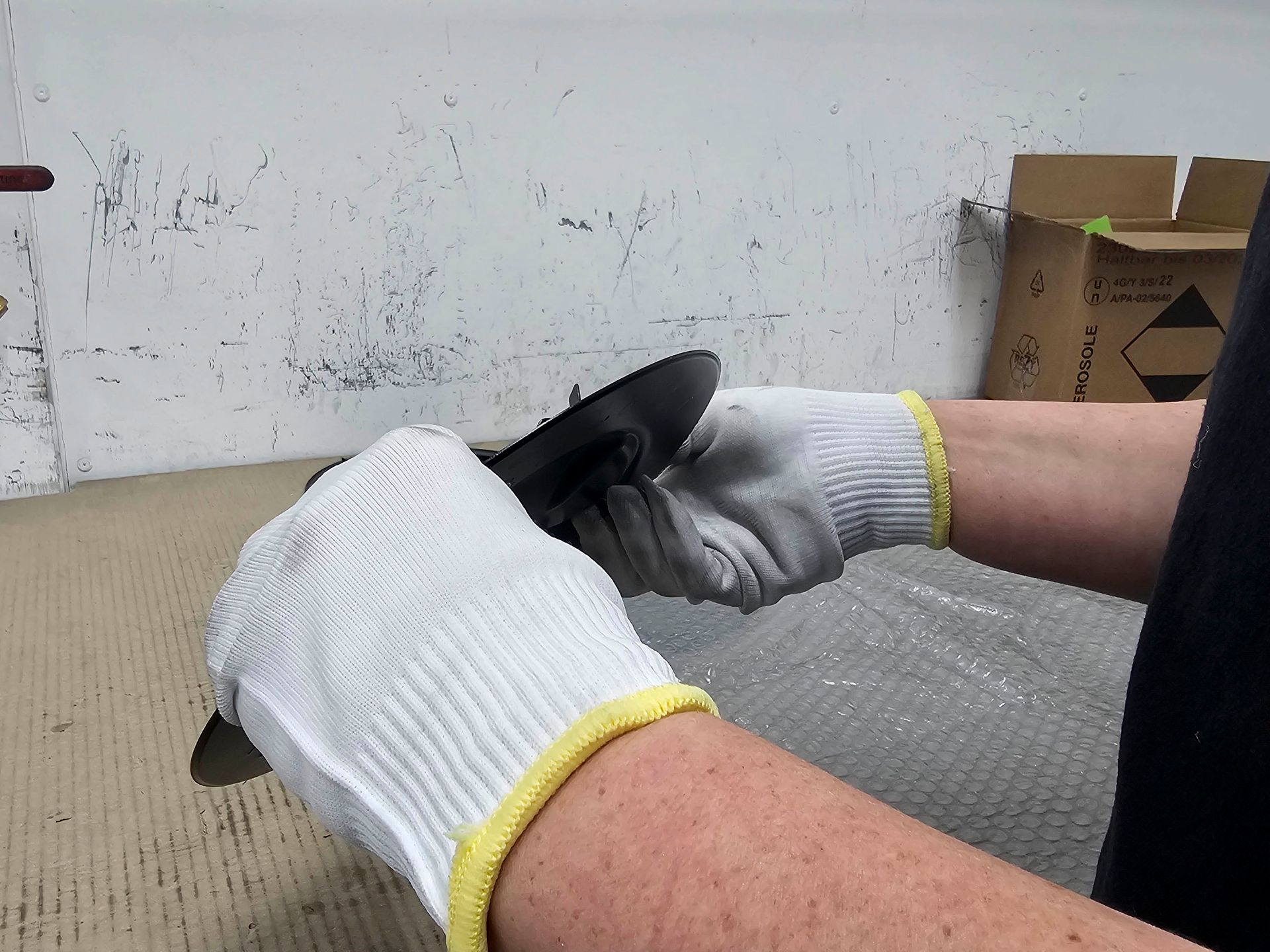 Eine Person mit weißen Handschuhen hält einen schwarzen Gegenstand