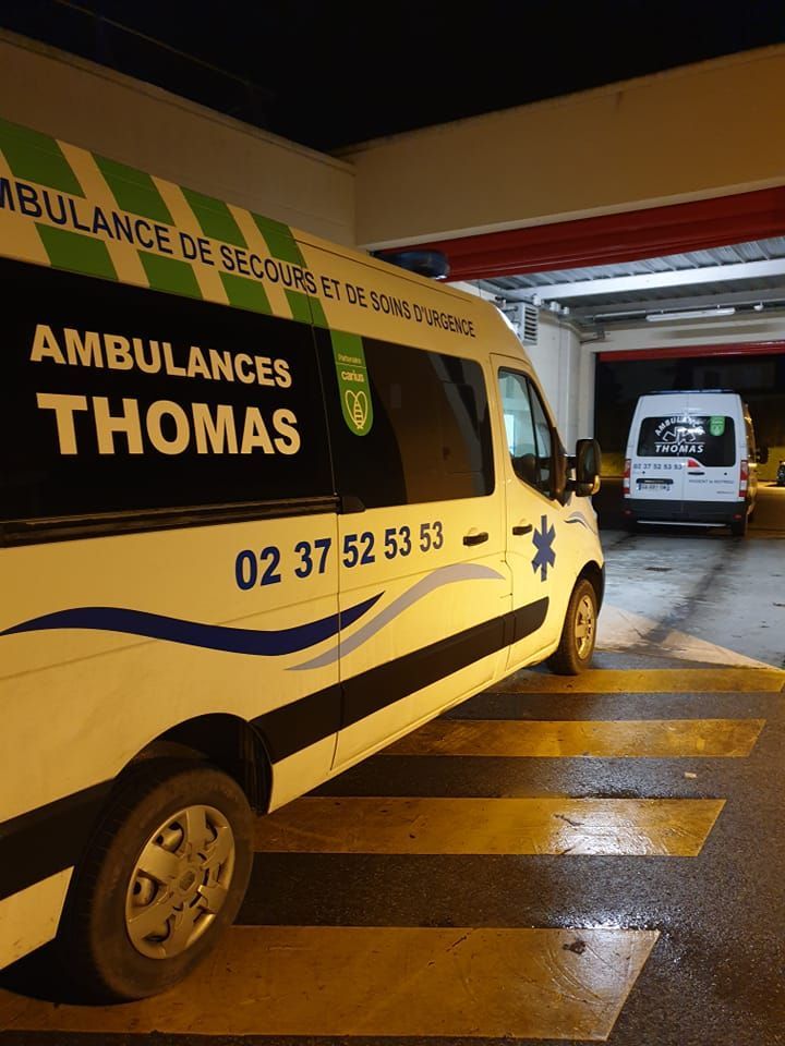 Deux ambulances Thomas en train de sortir d'un bâtiment de nuit