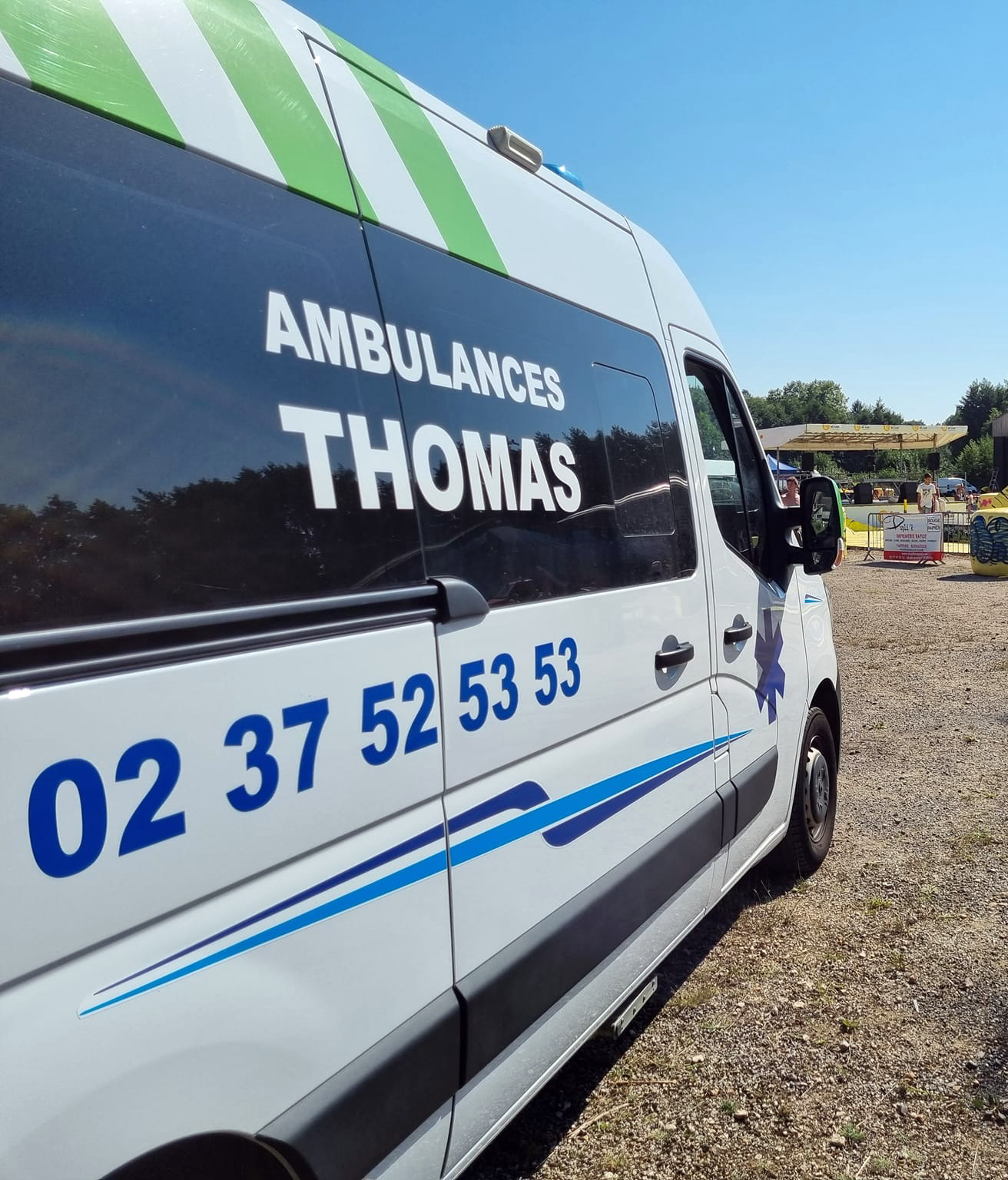 Un véhicule des Ambulances Thomas garé sur un parking où se déroule un évènement culturel