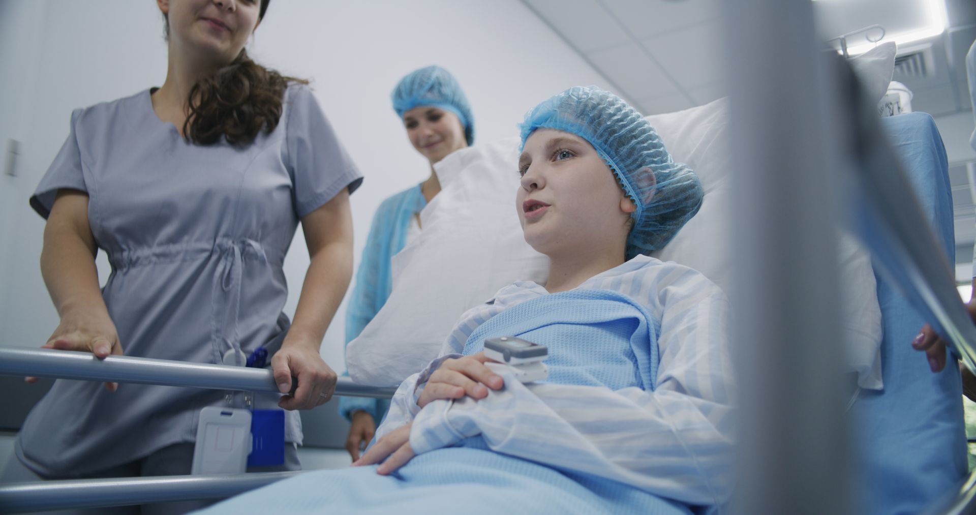 Une jeune fille souriante sur un brancard médical accompagnée d'infirmières