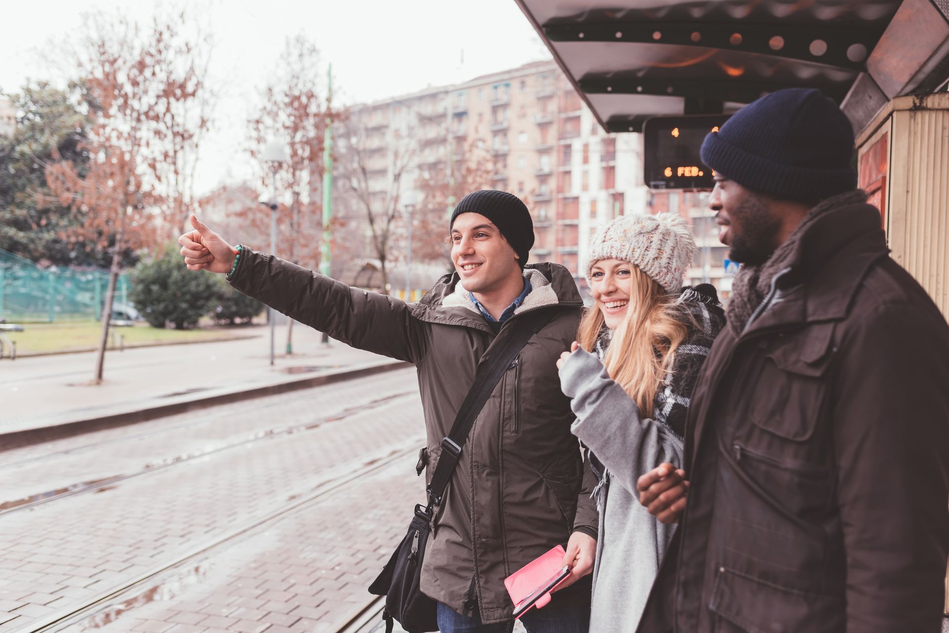 Groupe de trois personnes dont l'un fait un signe d'appel au taxi