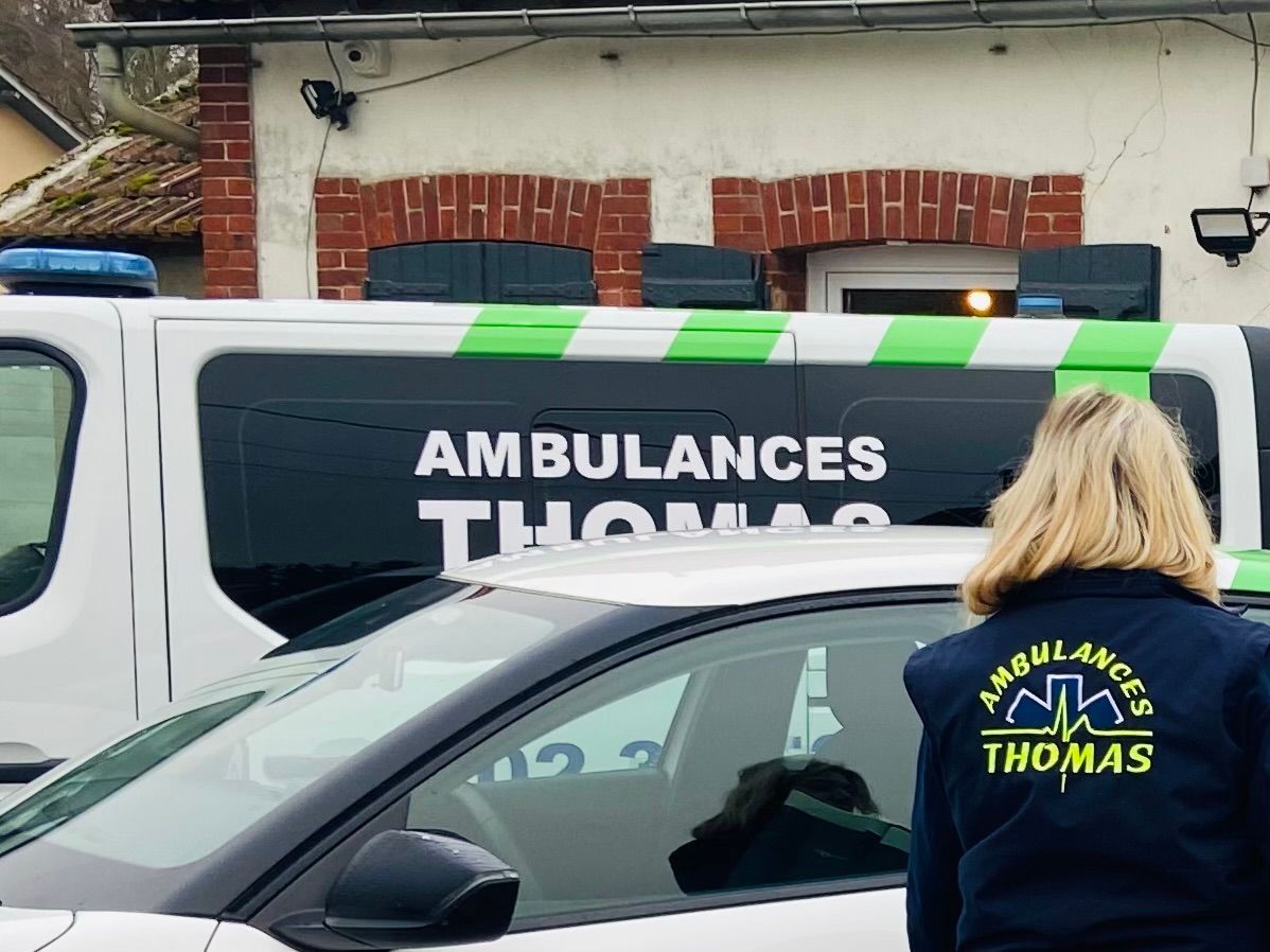 Ambulancière des Ambulances Thomas devant un véhicule gris