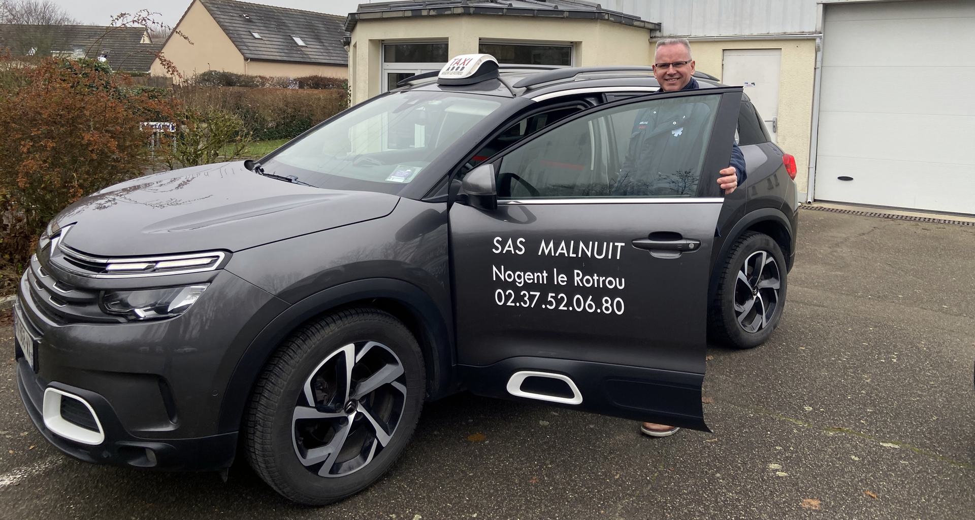 Homme ouvrant la portière d'un taxi noir de l'entreprise Malnuit