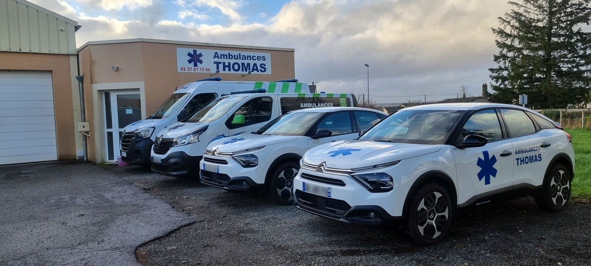 Ambulances et VSL garés devant un bâtiment dont l'enseigne est Ambulances Thomas