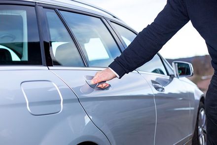 Eine Person öffnet die Tür eines silbernen Autos