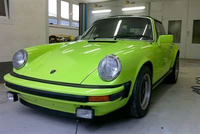 In einer Garage parkt ein leuchtend grüner Porsche.