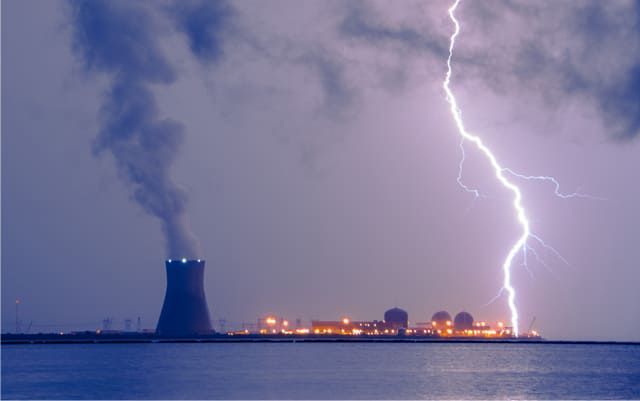 La foudre frappe une centrale nucléaire située près de l'eau, sous un ciel orageux.